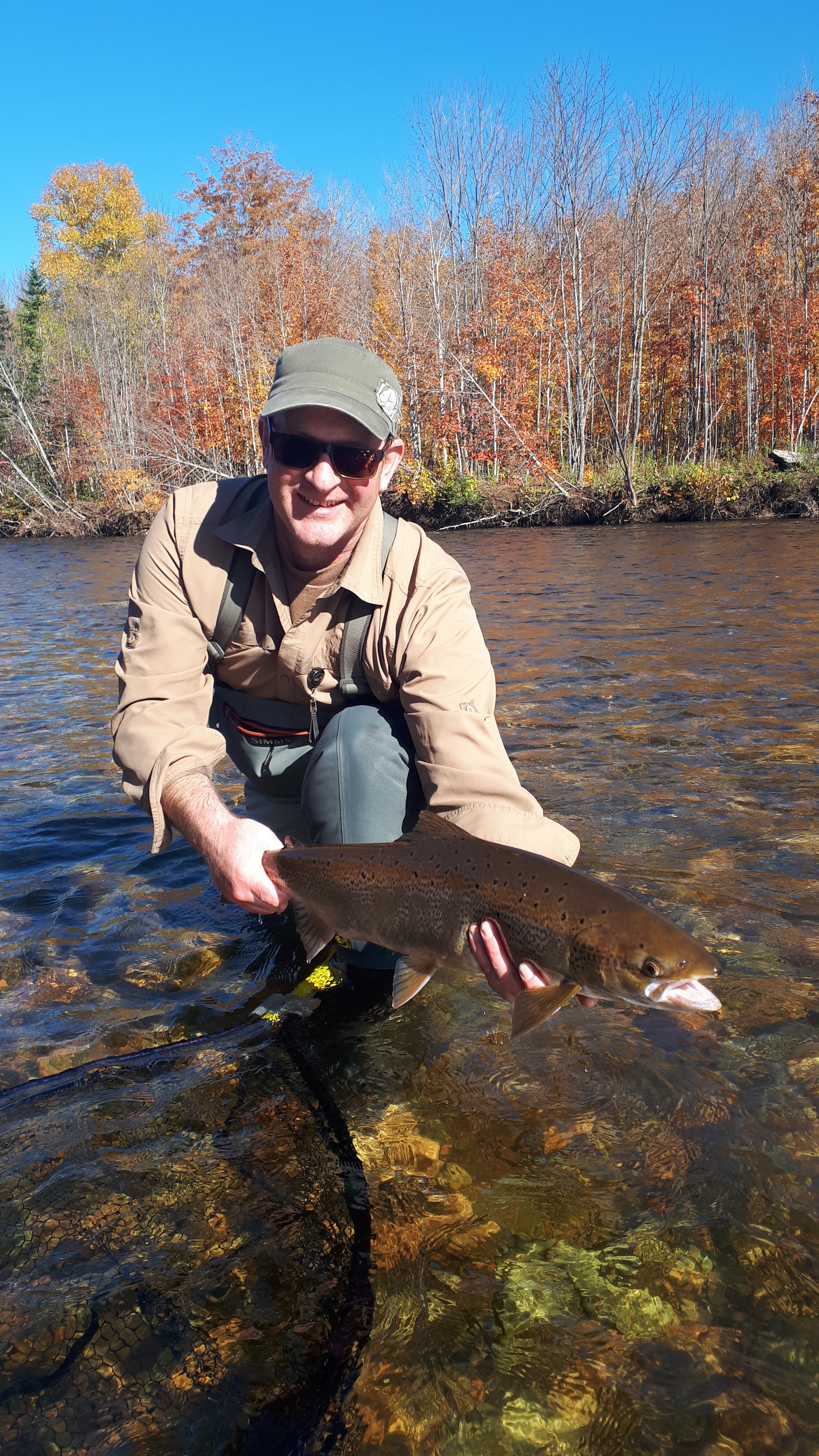 Man in a river holding a big fish