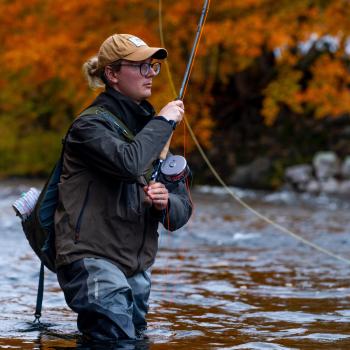 mitchell roberts casting on a river with fall colours in the background